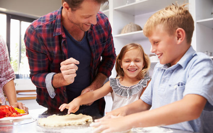 A photo of a father making pizza with kids