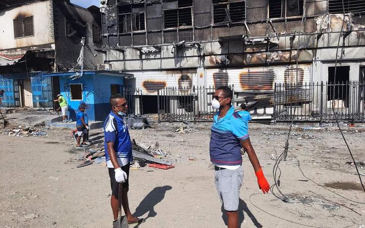 Members of the Fijian community in Honiara help BSP staff clean up. The bank was one of nearly 60 businesses torched by protesters last week.
