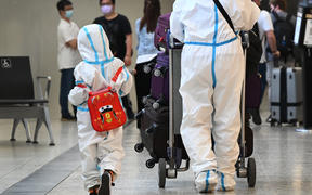 International travellers wearing personal protective equipment (PPE) arrive at Melbourne's Tullamarine Airport on November 29, 2021 as Australia records it's first cases of the Omicron variant of Covid-19. 