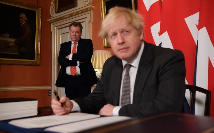 UK chief trade negotiator, David Frost (L) looks on as Britain's Prime Minister Boris Johnson (R) signs the Trade and Cooperation Agreement between the UK and the EU, the Brexit trade deal, at 10 Downing Street in central London on December 30, 2020. 