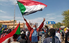A Sudanese protester waves the national flag during a rally to mark three years since the start of mass demonstrations that led to the ouster of strongman Omar al-Bashir, in the capital Khartoum on December 19, 2021.