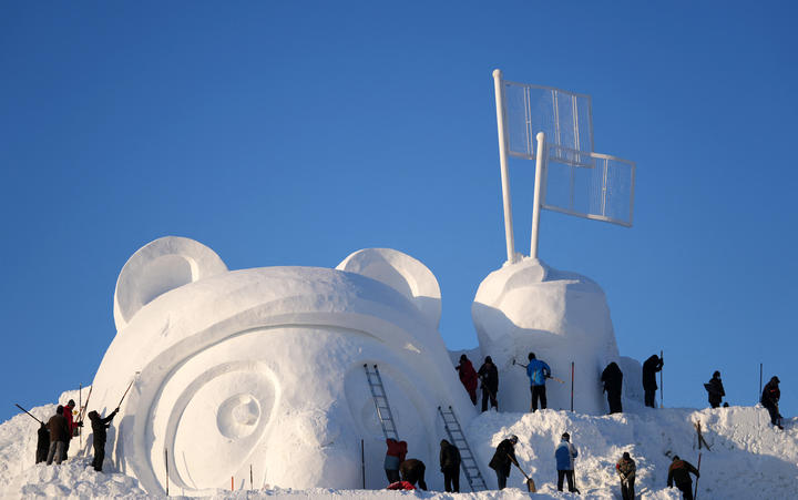 Escultores de nieve construyen la escultura de nieve principal en Nochebuena en la Exposición de Esculturas de Nieve de la Isla del Sol en Harbin, provincia de Heilongjiang, noreste de China.