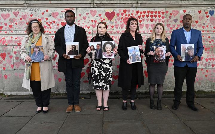 Members of the Covid-19 Bereaved Families for Justice group, from left, Deborah Doyle, Lobby Akinnola, Hannah Brady, Fran Hall, Jo Goodman and Charlie Williams, hold photos of those who lost their lives to coronavirus,  in front of the National Covid Memorial Wall,  in London on September 28, 2021. 