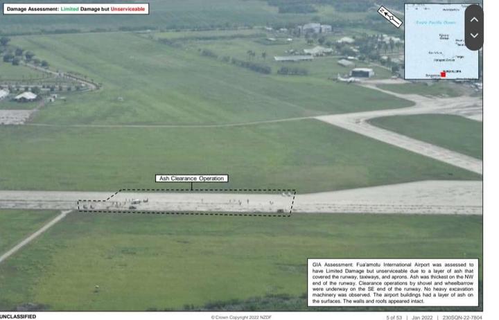 Fua'amotu International Airport in Tonga as seen from a New Zealand Defence Force P-3 Orion reconnaisance flight, after the eruption of Hunga-Tonga Hunga-Ha'apai. The image caption says workers are using shovels and wheelbarrows to clear volcanic ash from the runway.