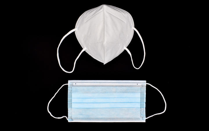 Disposable KN-95 mask vs thin surgical mask. COVID-19 prevention. H1N1, H5N1 safety measures. Isolated on black background.