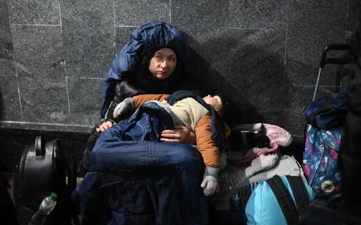 2022 年 2 月 26 日，在乌克兰西部的利沃夫中央火车站，一名妇女抱着熟睡的孩子坐在地上。