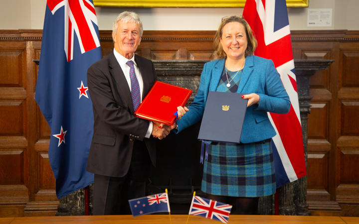 A man and a woman hold folders and shake hands.