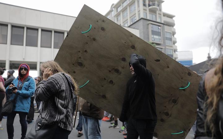 Protesters carry a wooden shield in the crowd.