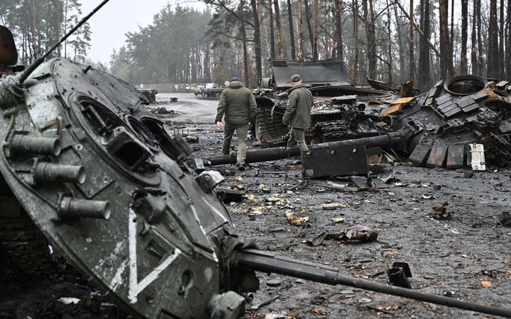 Ukrainian servicemen walk next to destroyed Russian tanks and armored personnel carriers in Dmytrivka village, west of Kyiv, on 2 April, 2022.