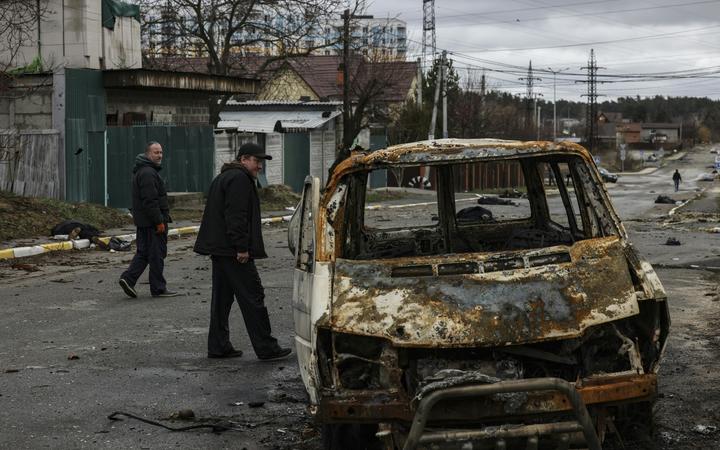 People walk through a street strewn with several dead bodies in Bucha, northwest of Kyiv.