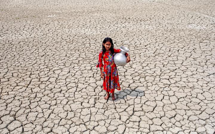 A girl walks over cracked ground after collecting drinking water from a pond near mangrove forest Sundarban in Satkhira, Bangladesh on 27 March, 2022. 
