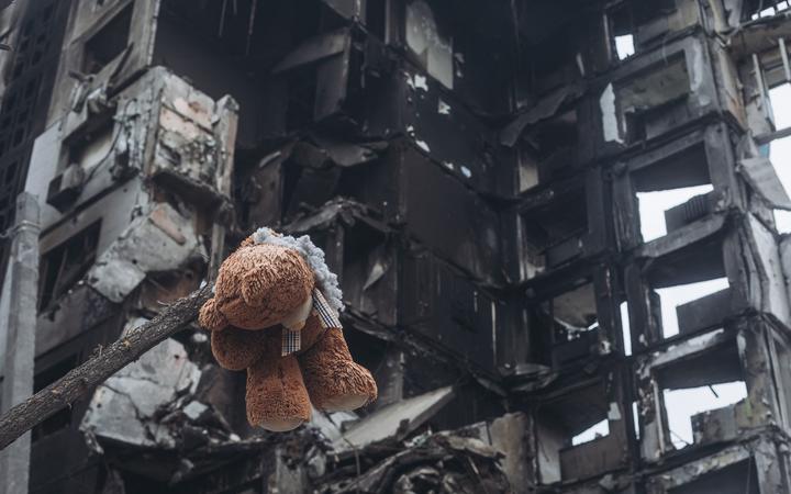 Borodyanka, UKRAINE - APRIL 6: A teddy bear hanging from a tree in front of a building bombed by the Russian army in Borodyanka (Ukraine), 6 April 2022. 