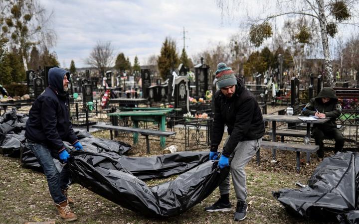 EDITORS NOTE: Graphic content / Workers line up bodies for identification by forensic personnel and police officers in the cemetery in Bucha, north of Kyiv, on April 6, 2022, 