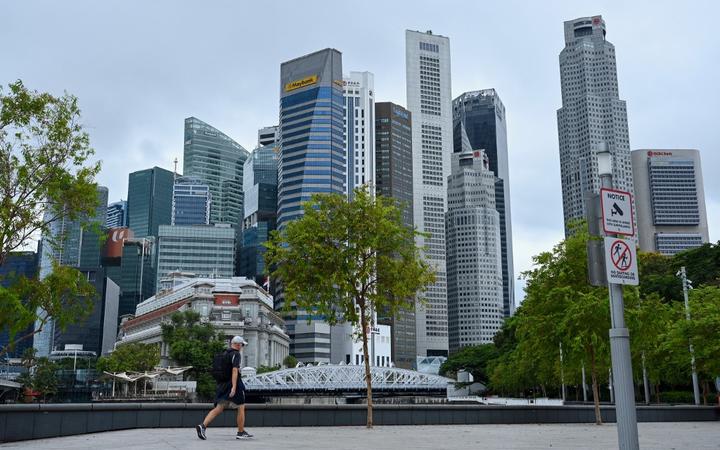 A man walks through a park next to financial business district in Singapore on April 7, 2022. (Photo by Roslan RAHMAN / AFP)