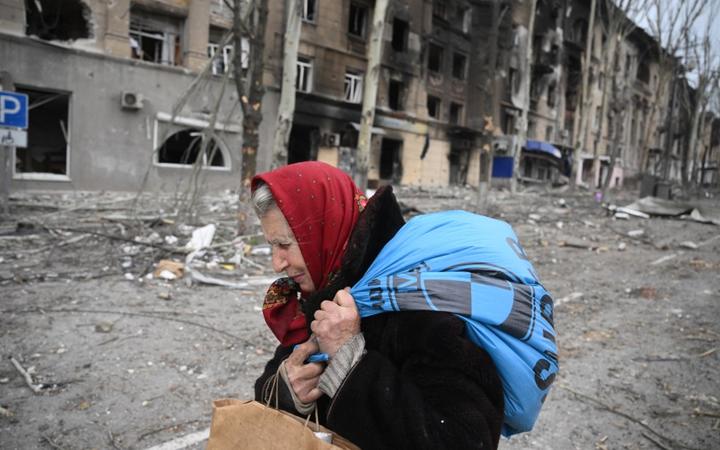 8161100 08.04.2022 An elderly woman passes by a destroyed house in Mariupol, Donetsk People's Republic. Ilya Pitalev / Sputnik (Photo by Ilya Pitalev / Sputnik / Sputnik via AFP)