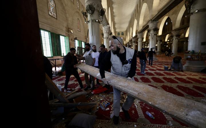Palestinians start to clean Al-Aqsa Mosque after Israeli forces raided Masjid Al-Aqsa, the first qibla of Muslims, in the Old City of East Jerusalem on April 15, 2022.