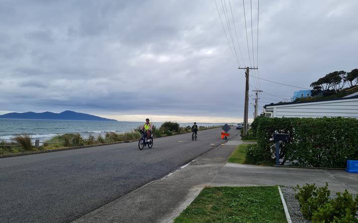 Cyclists ride along the waterfront in Pukerua Bay, a small seaside community