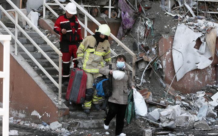 Rescue workers escort a local resident as she leaves a residential building which was hit by a missile strike in Odesa, Ukraine 24 April, 2022.