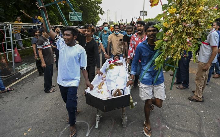在要求他辞职的示威活动中，大学生和一名打扮成斯里兰卡总理马欣达·拉贾帕克萨的示威者推着棺材。