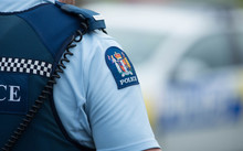 Close up of a police officer at an incident on a residential street. 6 July 2016.