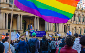 A protester waves a rainbow coloured flag at a marriage equality rally outside Town Hall in Sydney, Australia on August 9, 2015. 