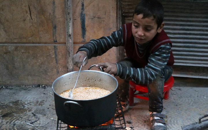 A child cooks on the street in Aleppo.