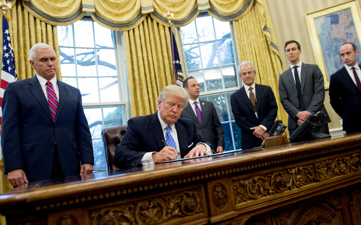 Donald Trump, seated, signed, three executive orders on Monday, including one banning any US-funded organisations from speaking about abortion.