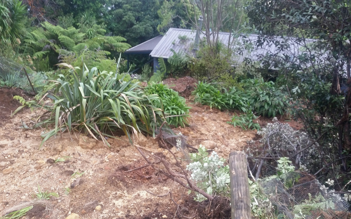 A slip nearly up to the roof of a holiday home in Whangamata, Coromandel Peninsula. The house is holding the mud back from moving onto the street.