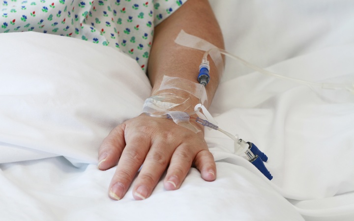 A file photo of a patient in a hospital bed with an IV drip in the arm 