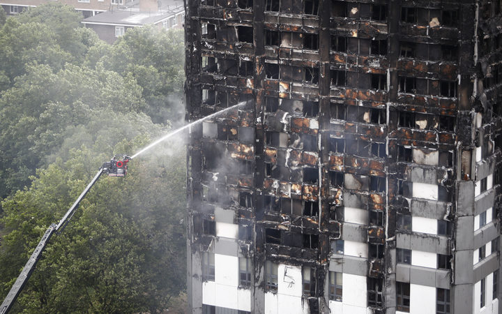 An automated hose sprays water onto Grenfell Tower.