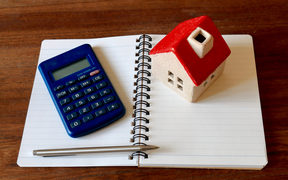 A calculator, a model of a house, a pen and a notebook - to illustrate financial planning and household budgets. 