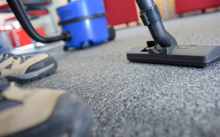 A cleaner uses a vacuum cleaner in an empty office.