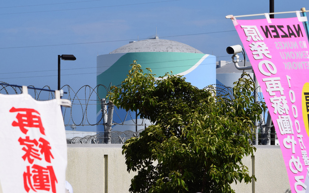 A nuclear reactor building can be seen through banners protesting the restarting of the Kyushu Electric Power plant in Sendai. 