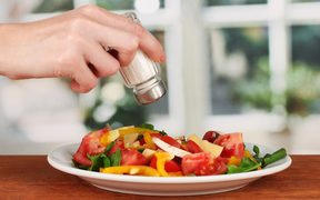 16738591 - hand adding salt using  salt shaker on bright background