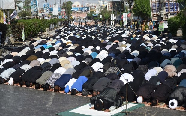 Pakistani Shiite Muslim devotees offer Friday prayers during the procession.