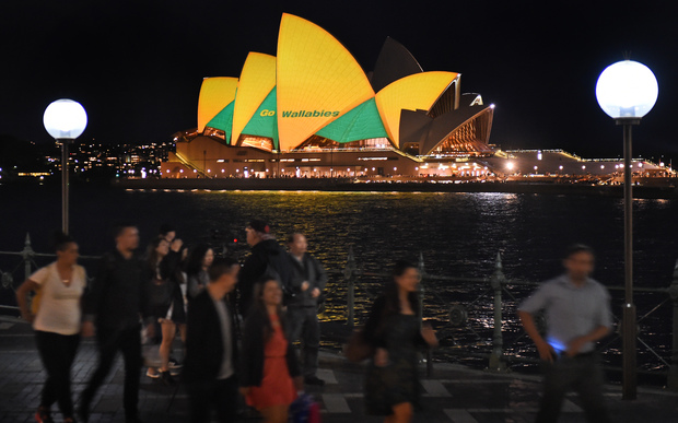 People pass the Sydney Opera House lit up in Australian colours in support of the Wallabies.