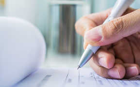 Hand with pen over application form on blure water glass background