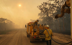 Firefighters refill their water from a water tanker in Pacific Drive in Deepwater National Park area of Queensland.