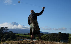Rangi Kipa swings a purerehua (Māori musical instrument) at the Taranaki settlement of Parihaka ahead of the Crown's 2017 formal apology for the military invasion of 1881.