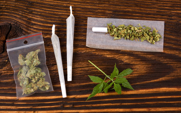 50549923 - marijuana background. cannabis joint, bud in plastic bag and hemp leaves on wooden table. addictive drug or alternative medicine.