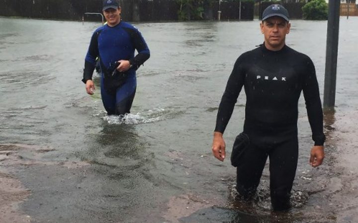 A handout picture provided by Queensland Police Service, taken on February 2, 2019 and release on February 3 shows two police officers wading in flood waters in Townsville. -