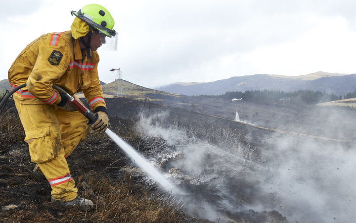 Fire fighter Lieutenant Oli Barnfather of the New Zealand Army fights an underground hotspot on the Port Hills of Christchurch. 