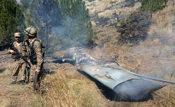 Pakistani soldiers stand next to what Pakistan says is the wreckage of an Indian fighter jet shot down in Pakistan-controlled Kashmir.