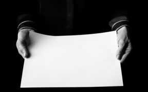 Black Mania. female hands isolated on black showing blank paper sheet