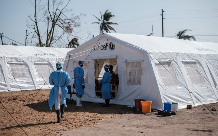 Medical staff stand in front of a treatment tent