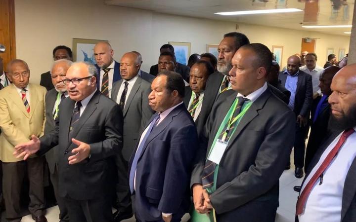 Papua New Guinea prime minister Peter O'Neill (with spectacles) flanked by coalition partners following a parliament session, 7 May 2019.