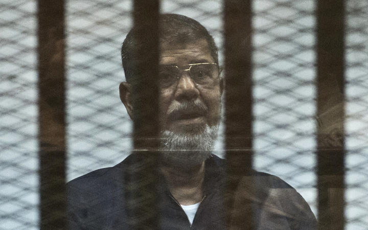 Mohamed Morsi stands behind the bars during his trial in Cairo in 2015.