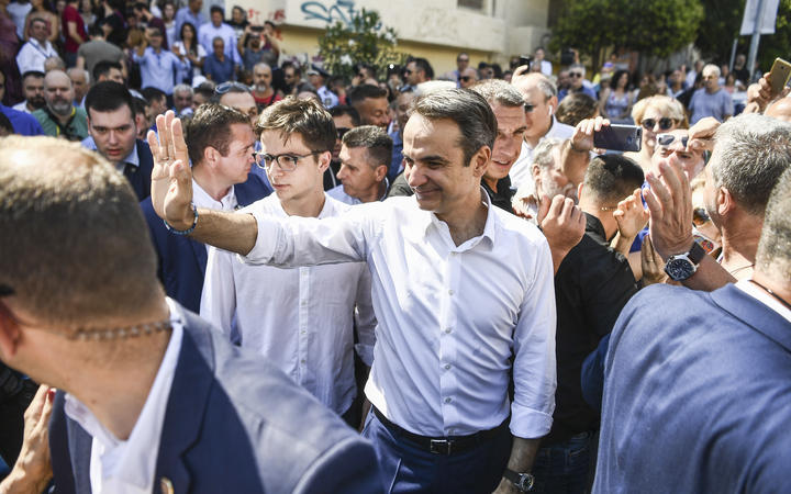 Greece's opposition party New Democracy leader Kyriakos Mitsotakis (centre) greets supporters as he leaves a polling station after casting his vote during general elections in Athens on 7 July, 2019.
