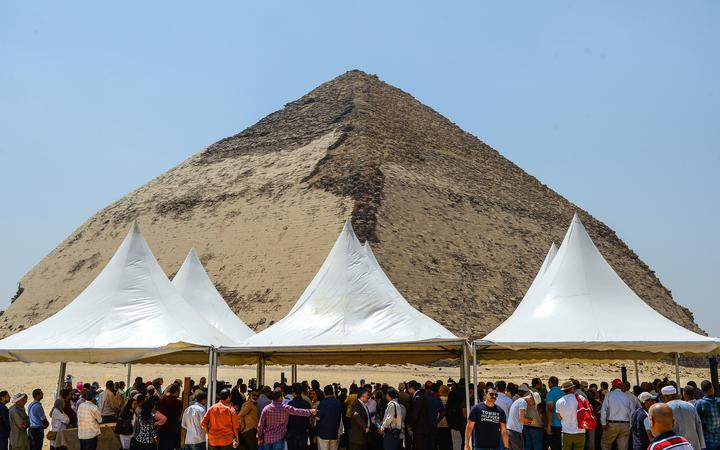 People gather during an inaugural ceremony in front of the Bent pyramid of King Sneferu, the first pharaoh of Egypt's 4th dynasty, in the ancient royal necropolis of Dahshur  south of  Cairo on July 13, 2019. 