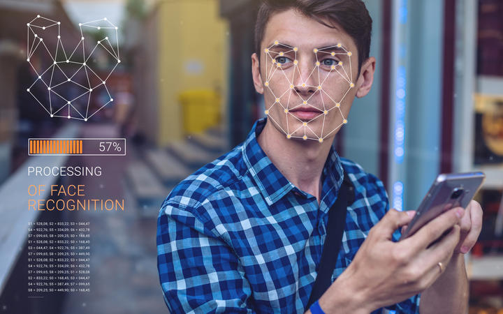 Biometric verification. Modern young man with the phone. The concept of a new technology of face recognition on polygonal grid is constructed by the points of IT security and protection